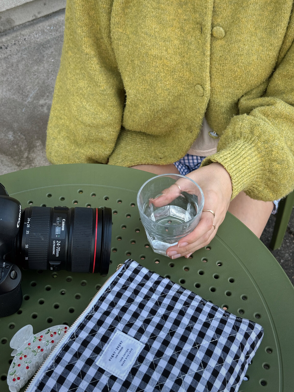 Camera and gingham pouch at a green bistro table